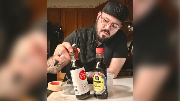 Soy Sauce vs Tamari: What's the Difference? A man inspecting a bottle of Tamari and Soy Sauce.